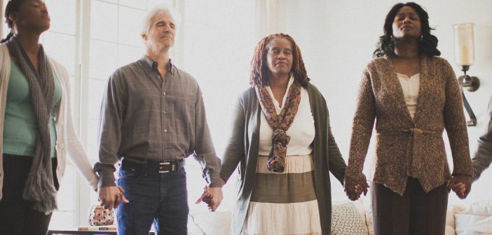 Photo of a diverse group of people holding hands in prayer