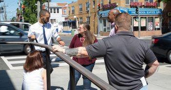 Photo of people having a conversation near a busy intersection