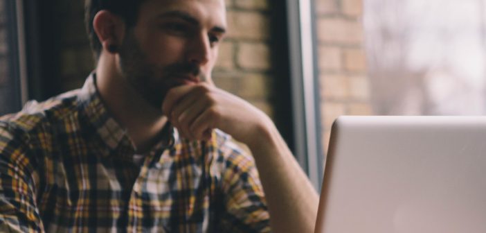 A photo of a person in a cafe contemplating what is on their computer screen