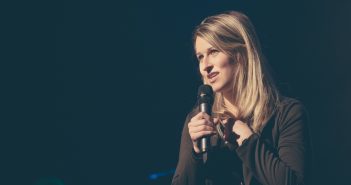 Photo of a person with a microphone giving testimony in front of the church