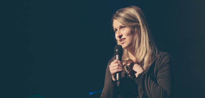 Photo of a person with a microphone giving testimony in front of the church