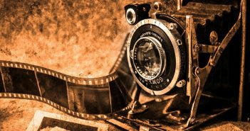 Sepia-toned photo of an old camera, film, and photographs