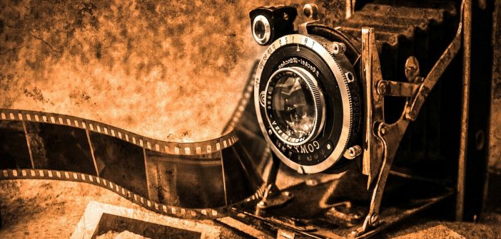 Sepia-toned photo of an old camera, film, and photographs