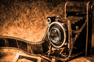 Sepia-toned photo of an old camera and roll of film