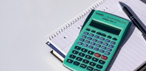 Photo of a calculator, pen, and spiral notebook