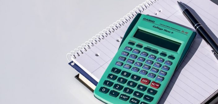 Photo of a calculator, pen, and spiral notebook