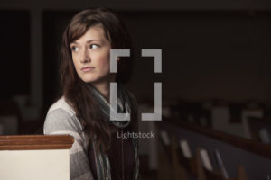 Photo of women sitting in a pew looking over her shoulder.