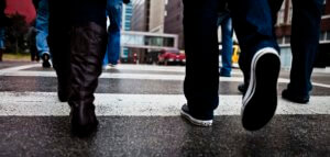 Closeup of a group of people's legs crossing a street in the city