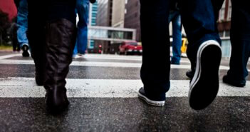 Closeup of a group of people's legs crossing a street in the city