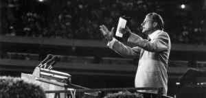 Billy Graham addresses a large crowd. CREDIT: Keystone / Getty Images / Universal Images Group, Rights Managed / For Education Use Only
