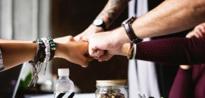 Group fist bump from the outstretched arms of a diverse group of young adults