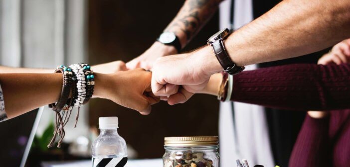 Group fist bump from the outstretched arms of a diverse group of young adults