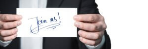 Stock photo of a man holding a handwritten note saying "join me.: