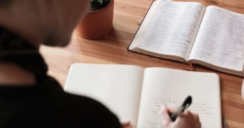 Pastor working a sermon with an open Bible and notepad on the desk