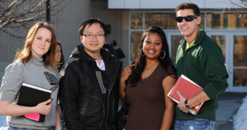 Group of diverse students standing in front of a suburban high school