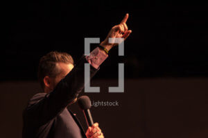Photo of a man preaching gesturing with one finger raised.