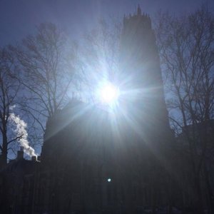 Morning sunlight appearing behind the facade and spire of Riverside Church in New York.