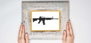 Hands holding a framed image of an assault rifle