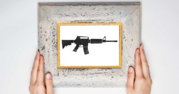 Hands holding a framed image of an assault rifle