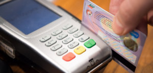 Close up of a person swiping a credit card through a credit card reader