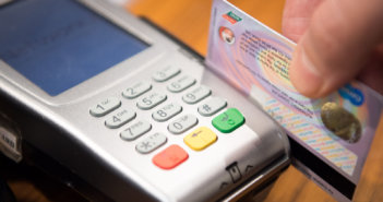 Close up of a person swiping a credit card through a credit card reader