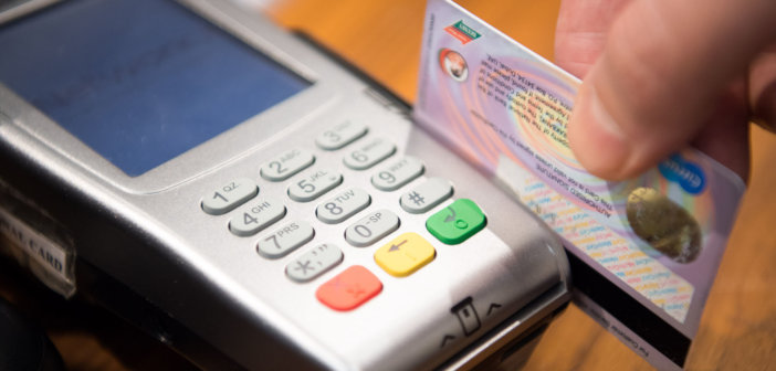 Close up of a person swiping a credit card through a credit card reader