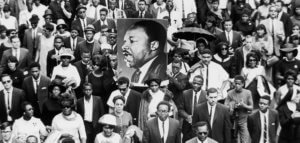 A large crowd of mourners follow the casket of Dr Martin Luther King Jr through the streets of Atlanta, Georgia. Two men carry a large sign with King's face. CREDIT: Hulton Archive / Getty Images / Universal Images Group