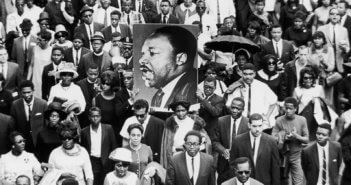 A large crowd of mourners follow the casket of Dr Martin Luther King Jr through the streets of Atlanta, Georgia. Two men carry a large sign with King's face. CREDIT: Hulton Archive / Getty Images / Universal Images Group