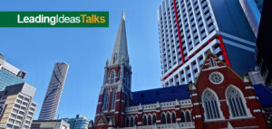 Old brick church surrounded by tall modern buildings