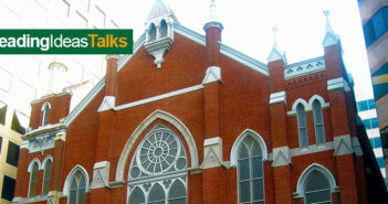 Old brick church surrounded by tall modern buildings