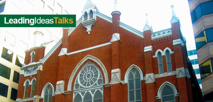 Old brick church surrounded by tall modern buildings