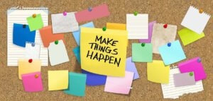 Cork board full of thumbtacked notes including a big one that says MAKE THINGS HAPPEN!