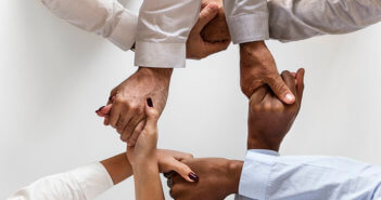 Diverse group of people clasping hands together