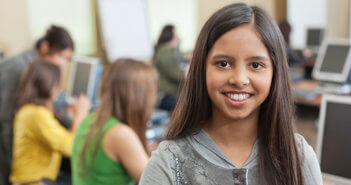 Smiling student standing in a school computer lab