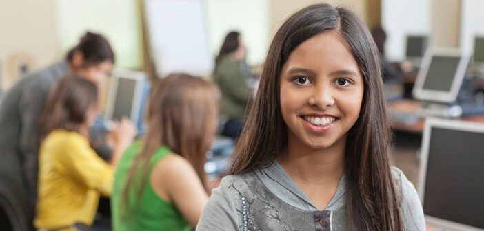 Smiling student standing in a school computer lab