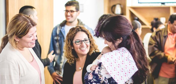 Groups of people chatting after church, including one holding an infant