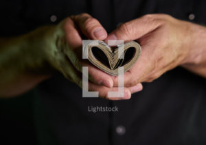 Currency rolled into the shape of a heart in a man's hands.