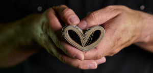 Person's hands holding paper currency folded into the shape of a heart