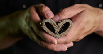 Person's hands holding paper currency folded into the shape of a heart