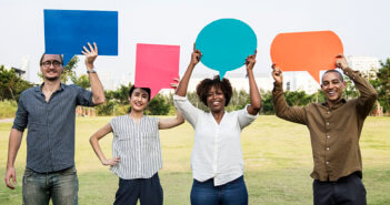 Four millennials holding up cardboard speech bubbles