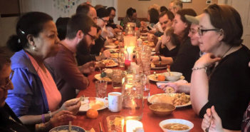 People sitting at a long table having animated conversations while eating dinner at Simple Church in Massachusetts