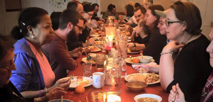 People sitting at a long table having animated conversations while eating dinner at Simple Church in Massachusetts