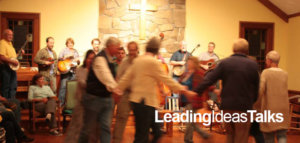 People whirling in a circle to live bluegrass music at a square dance at Wild Goose Christian Community