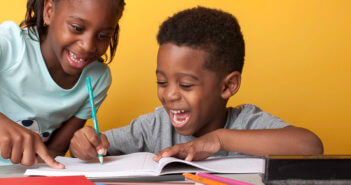 Smiling kids writing in a notebook