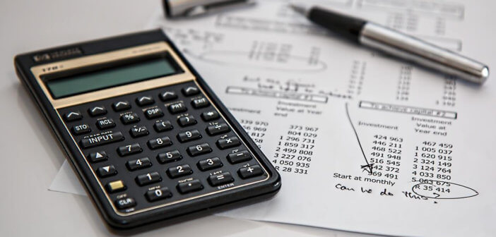 Calculator, ink pen and financial sheets