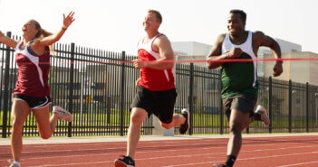 Runner surging ahead to cross the finish line ahead of other runners in a race