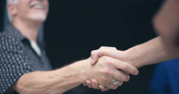 Person warmly shaking hands with another