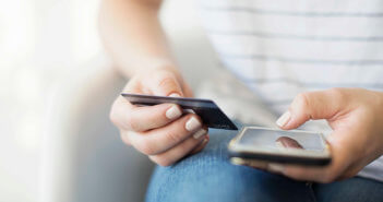 Young person holding a credit card and mobile phone