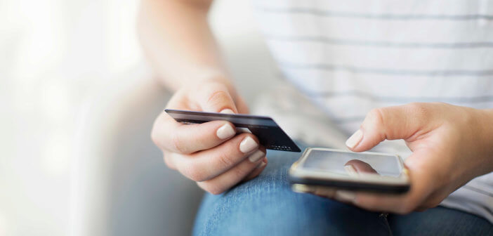 Young person holding a credit card and mobile phone