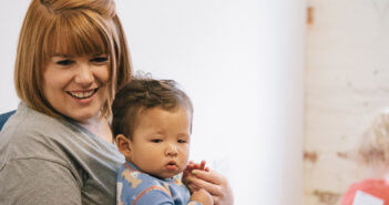 Smiling child care working holding a cute toddler